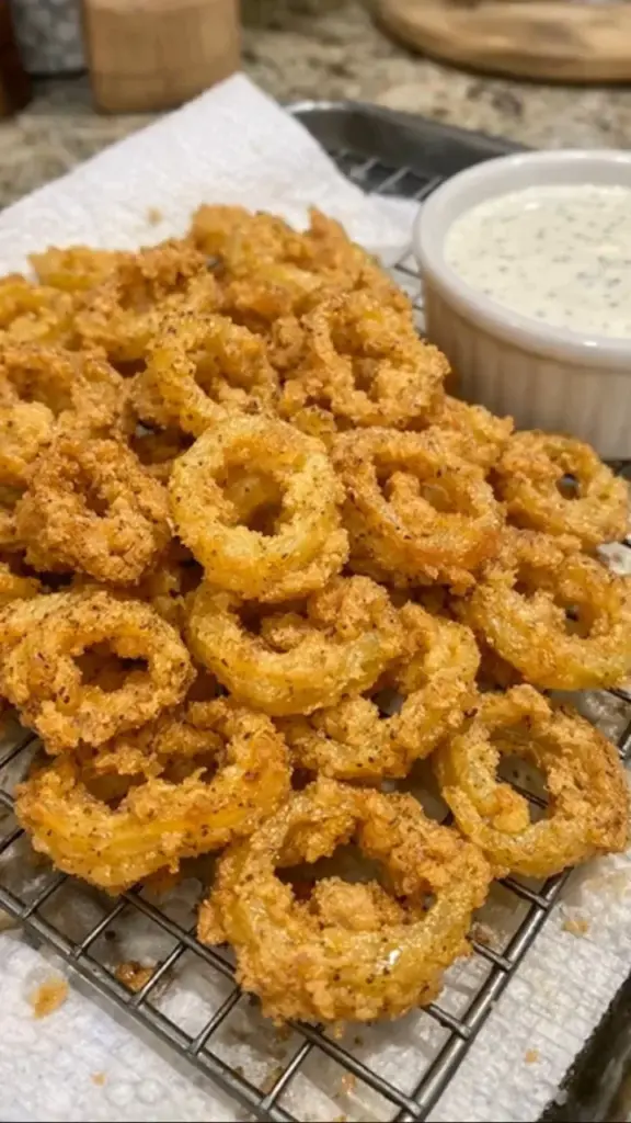 Plate of crispy fried banana peppers served with a dipping sauce.