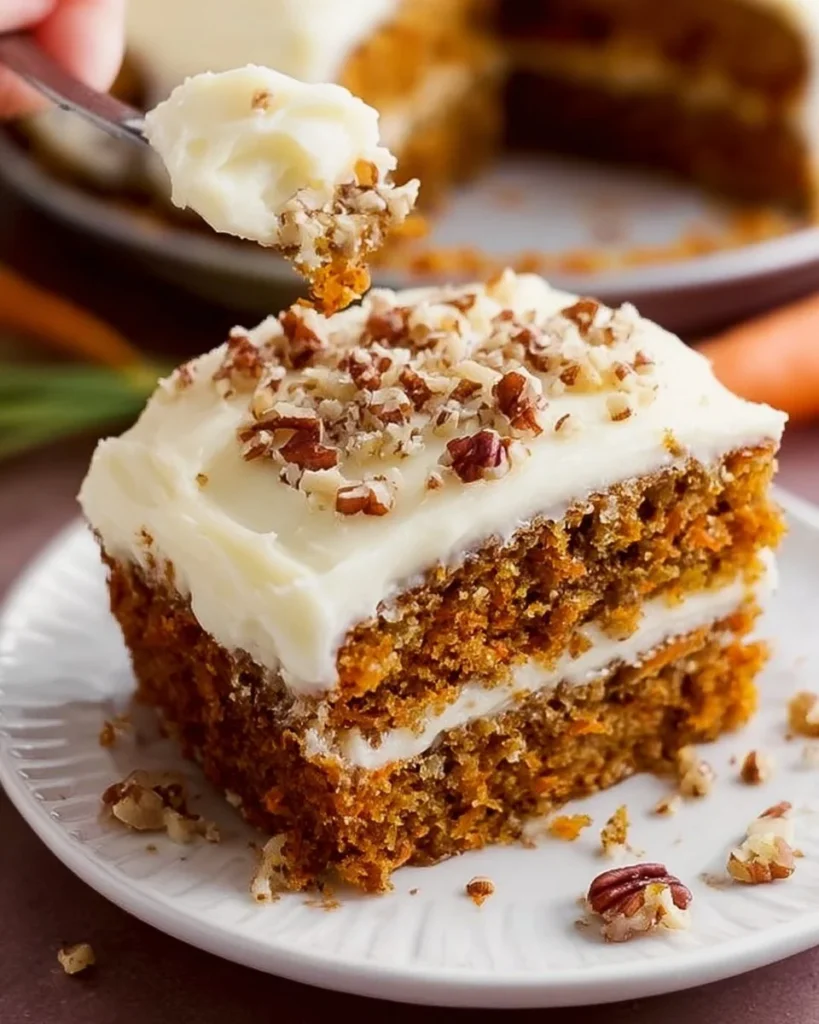 Slice of sugar-free carrot cake with brown butter cream cheese frosting on a plate.