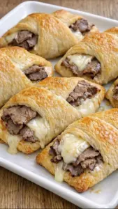 Cheesy garlic steak crescent rolls on a plate, garnished with herbs