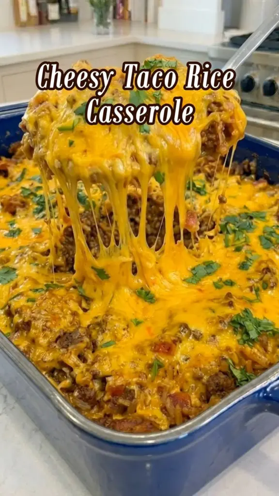 Cheesy Taco Rice Casserole baked in a dish topped with cheese and herbs