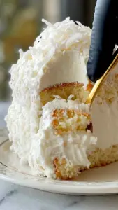 Slice of Coconut Cloud Cake topped with coconut flakes and whipped cream
