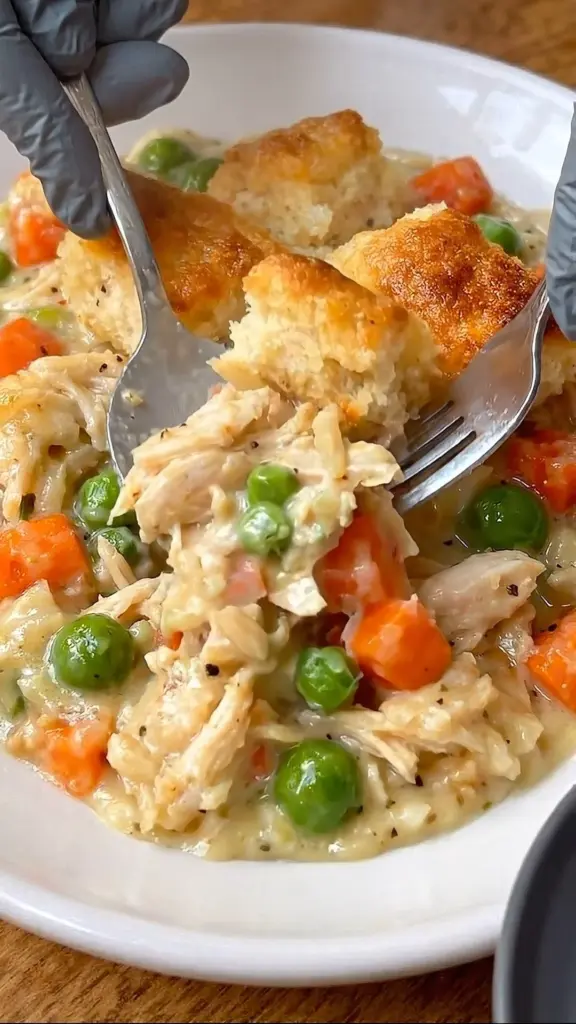 Creamy chicken pot pie bowl topped with golden flaky crust and fresh vegetables