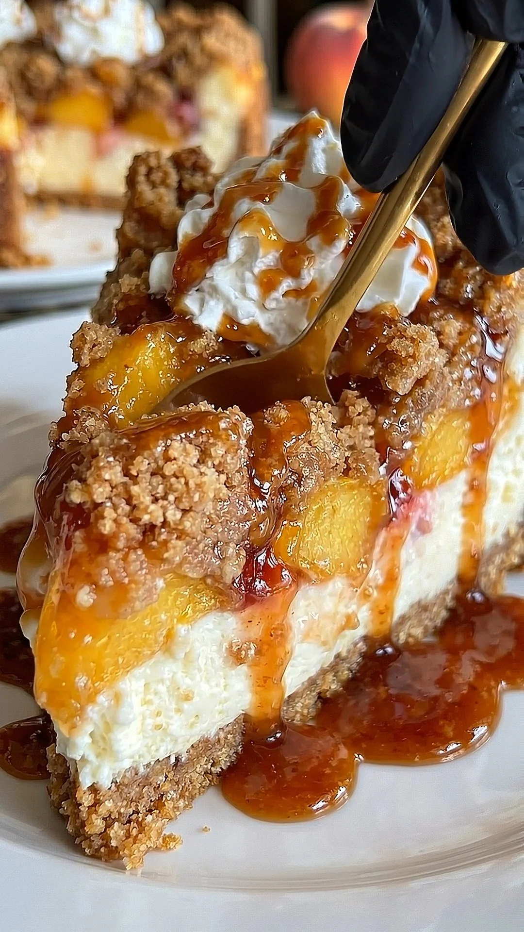 Delicious Peach Cobbler Cheesecake topped with fresh peaches and a golden crumble.