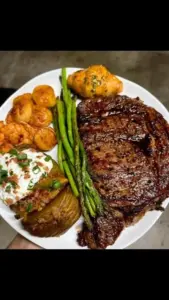 Ribeye steak with scallops, shrimp, and grilled asparagus on a plate