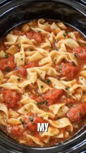 Bowl of Slow Cooker Amish Tomato Noodle Soup with noodles and fresh tomatoes.