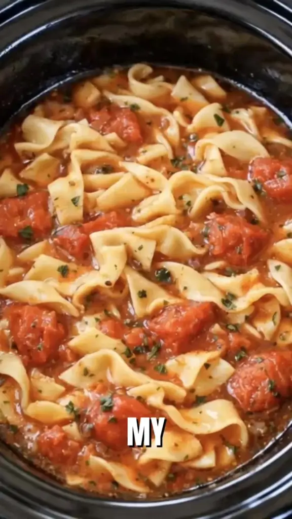 Bowl of Slow Cooker Amish Tomato Noodle Soup with noodles and fresh tomatoes.