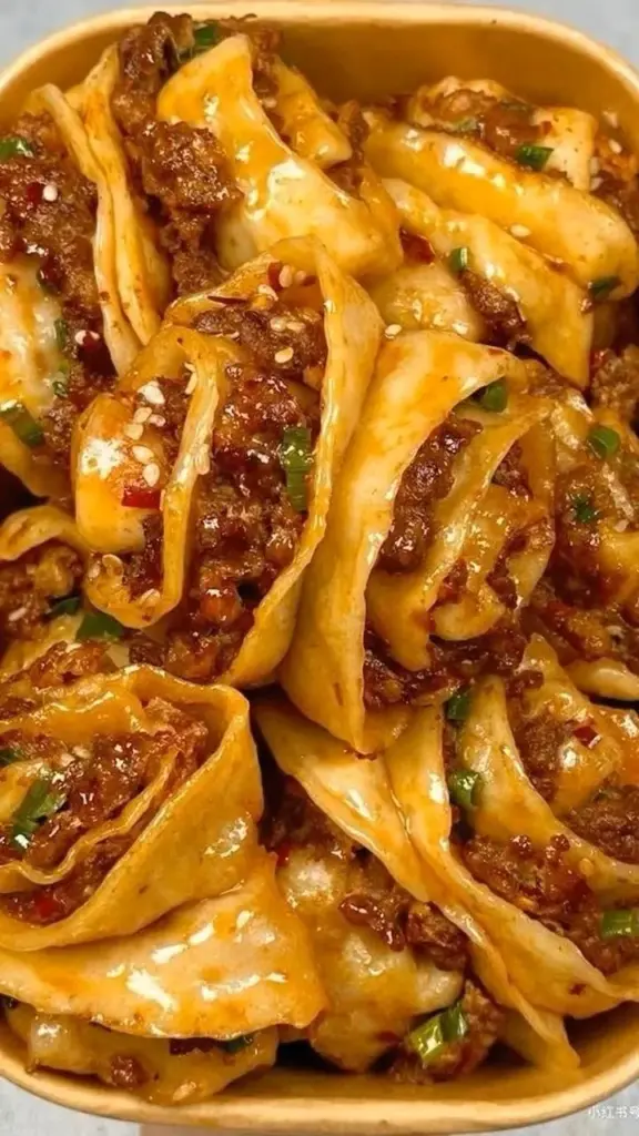 Spicy beef dumplings served with dipping sauce on a plate.