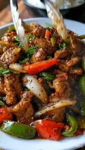 A delicious plate of spicy black pepper chicken stir-fry with vibrant vegetables.