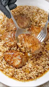 Tender garlic butter beef medallions with onion rice dish served on a plate.